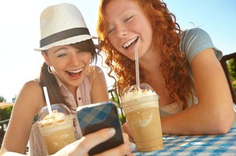Two Gen Z friends enjoying iced coffee.