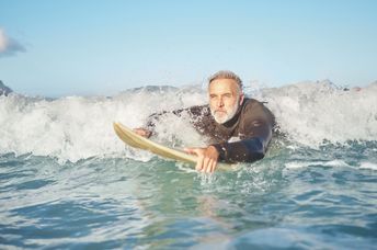 a senior man bodyboarding in the surf.