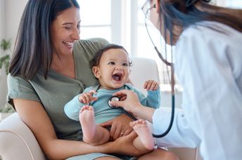 A baby smiles during a medical checkup.