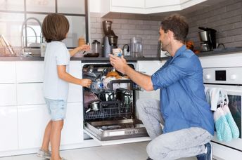 Father and son load a dishwasher.