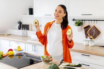 A pregnant woman eating a healthy salad with avocado.