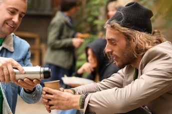 Giving a person on the street a hot drink on a cold morning.