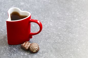 A mug on a table with chocolates next to it.