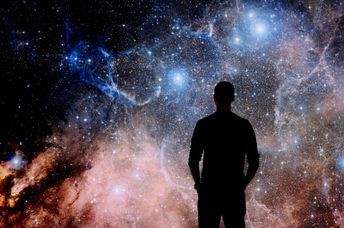 A young man standing in front of a huge image of space.