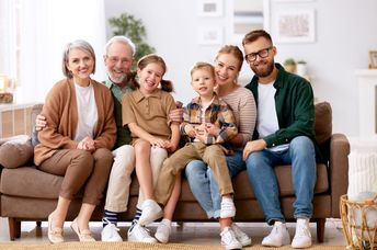 A family smiles while sitting on a couch.