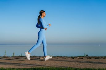 A woman walks along a waterside path.