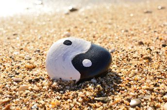 Yin and Yang painted on a rock by the sea.