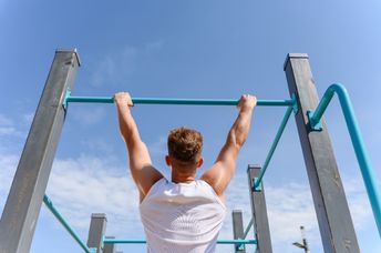 A man hangs from a bar.