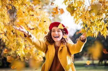 A woman throws leaves in the air.