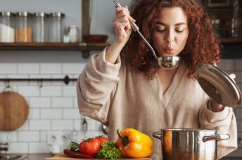 A woman boiling vegetables to make a healthy soup.