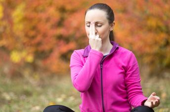 Woman practicing alternate nostril breathing.