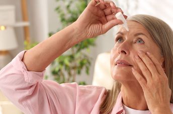 A senior woman using eye drops to improve her vision.