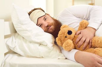 Adult man sleeping with a stuffed animal.