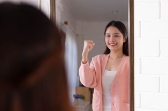 A woman smiles while looking at her reflection.