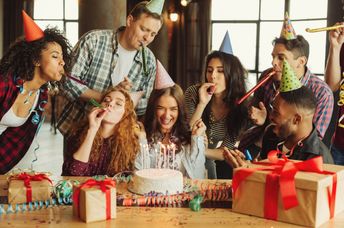 A group of friends celebrate together around a cake.