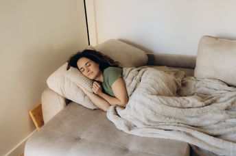 A woman rests peacefully under a warm blanket.
