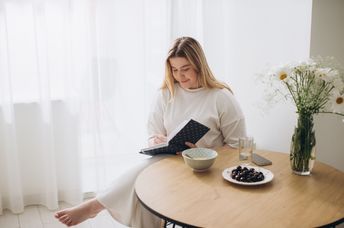 A woman sits and writes in a journal.