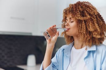 A woman drinks water from a glass.