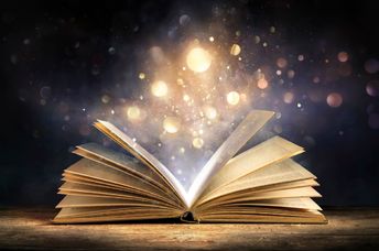 An open antique book softly glows with warm golden light.