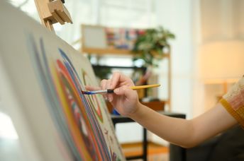 A close up of a female artist painting abstract artwork.