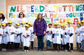 Shari Arison stands with a group of children wearing “Doing Good” shirts.