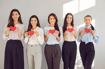 Women hold red paper hearts.