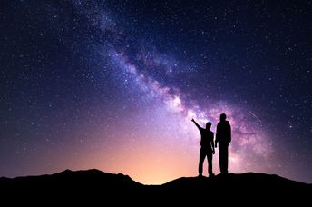 A silhouette of a family with a backdrop of the milky way.