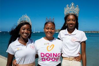 Three women wearing tiaras and Good Deeds Day shirts stand by the water.