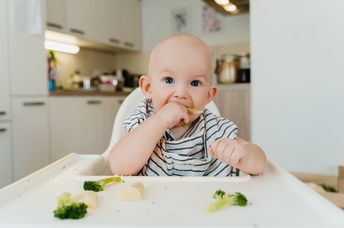 A baby boy eats vegetables.