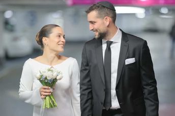 A couple holds hands on their wedding day in an underground shelter.
