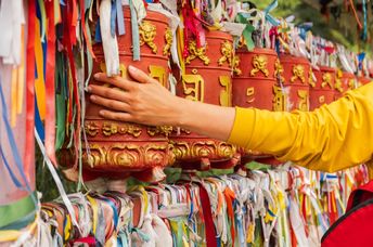 A pilgrim touches a turning spinning Buddhist prayer wheel.