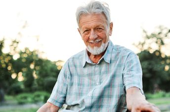 An elderly man smiling outdoors.