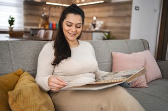A woman looking at a photo album while sitting on a couch.