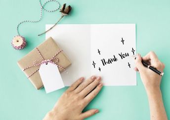 A woman writes thank you on a card