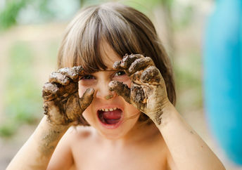 child with muddy hands