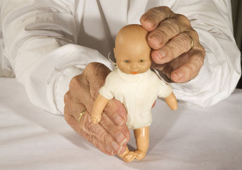 Old demented person plays with toy doll