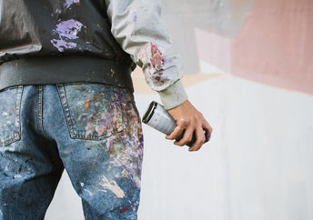 Graffiti artist with aerosol spray bottle near the wall