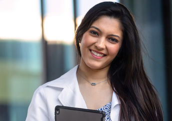 Native American student wearing a white hospital coat.