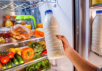 Woman checking on expiration date on milk.