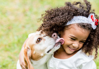 Girl being licked by her pet dog.