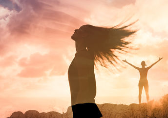 Woman triumphant at sunset