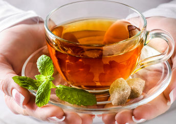 A woman holding a cup of headache soothing tea.