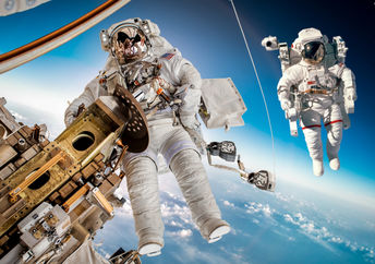 The International Space Station in outer space with two astronauts floating outside.