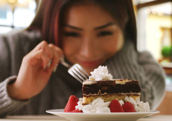 A woman happily indulges in a fancy dessert.