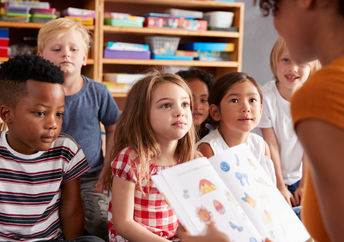 A teacher reads a story to young students.
