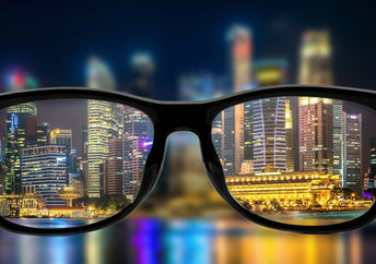 Looking through the lenses of glasses and seeing a bright cityscape at night.