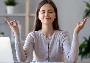 A woman takes a break from work to mediate and regain energy.