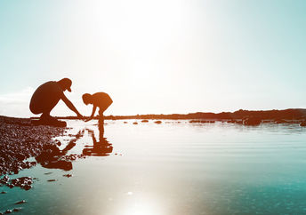 Silhouette of father and son playing on the beach at sunset