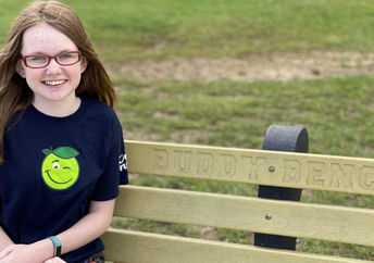 Sammie sitting on a buddy bench made from bottle caps.