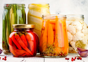 An appetizing selection of marinated pickled vegetables in glass jars.